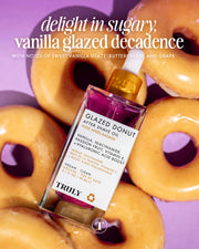 A bottle of Glazed Donut After Shave Oil rests atop vanilla-glazed donuts. The label features passion fruit and vitamin E for hydrating post-shave care. Above, the text says, “delight in sugary, vanilla glazed decadence.”.