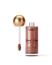 A bottle of Truly Beauty Luxury Peptide Lip Oils with a gold-capped applicator wand sits against a pale white background. The bottle holds 0.42 fl. oz. (12 ml) of product.