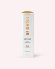 A white cylindrical bottle of The Brightening Body Serum by Truly Beauty, formulated to target dark spots, stands upright with gold and black text on a pale pink background.