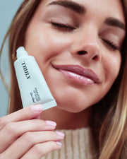 Woman holding a TRUAX skincare product close to her face