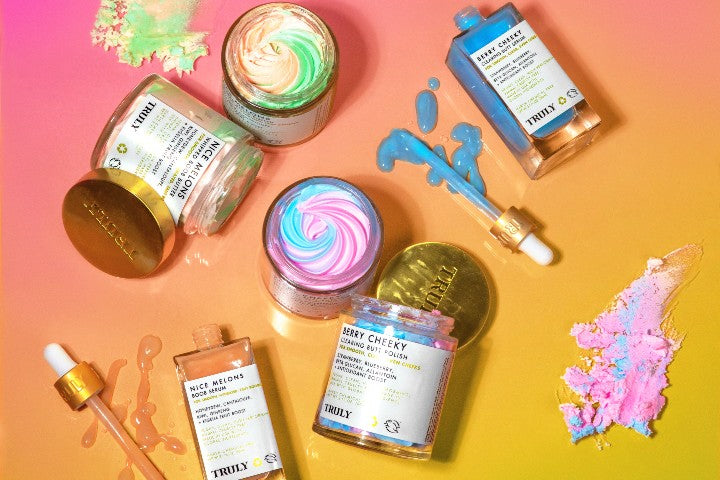 Truly beauty products spread out with colorful orange and pink background