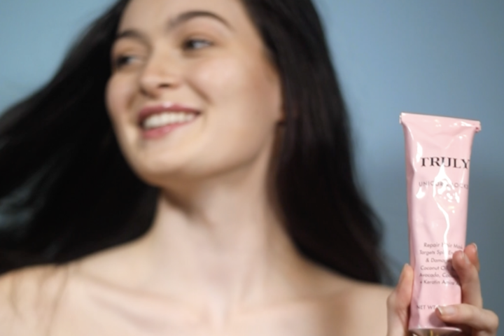 young women with dark hair holding Truly's Unicorn hair mask