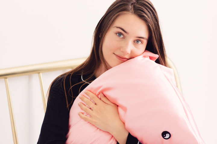 Young dark haired woman hugging pink pillow