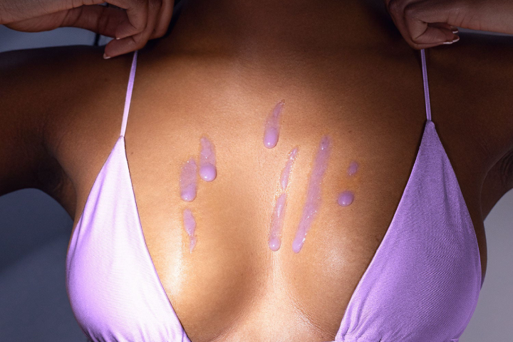 Woman in bikini with Truly's acai your boobies serum drops on chest