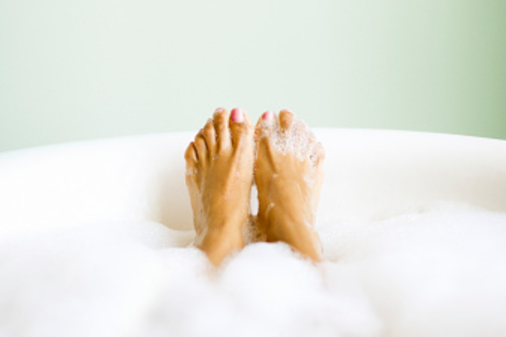 person's feet in bubble bath
