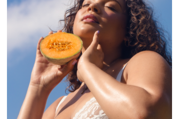 Woman holding a halved cantaloupe melon. 