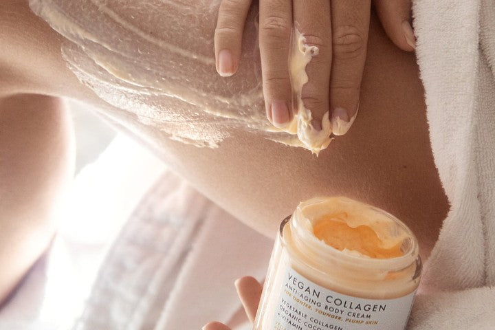 A hand applying body cream to leg beside a jar of vegan collagen body cream