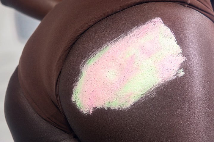 closeup of woman's butt with swipe of Buns of Glowry polish on cheek