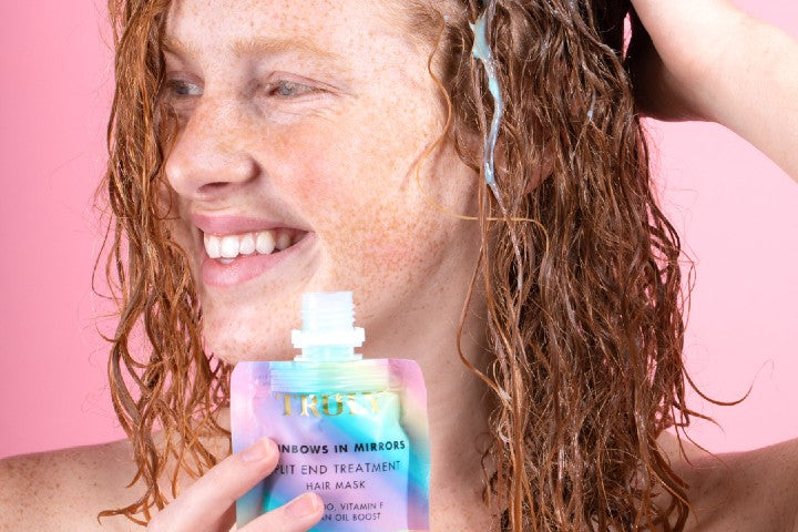 young woman holding rainbow hair mask