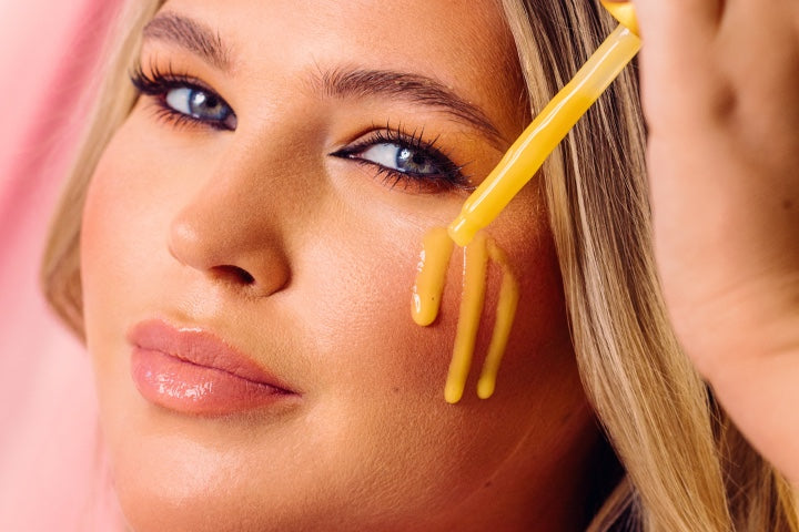young blonde haired woman applying serum to cheek