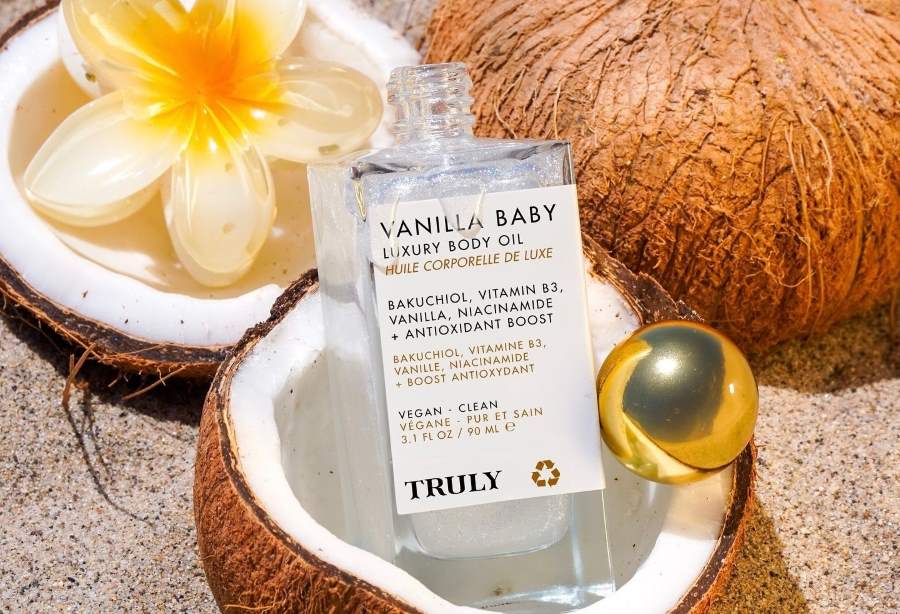 bakuchiol benefits for skin | truly's vanilla baby body oil with bakuchiol in coconut shell with sandy background