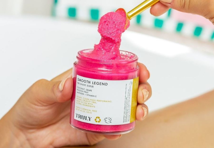 how to use body scrub | woman scooping out truly's smooth legend scrub with gold scoop