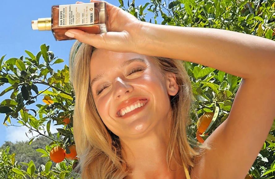 summer skincare routine 2025 | young blonde woman smiling and holding Truly's Sun Drops