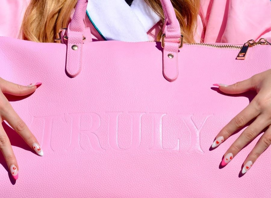 can you bring sunscreen on a plane | woman's hands over Truly's pink duffle bag