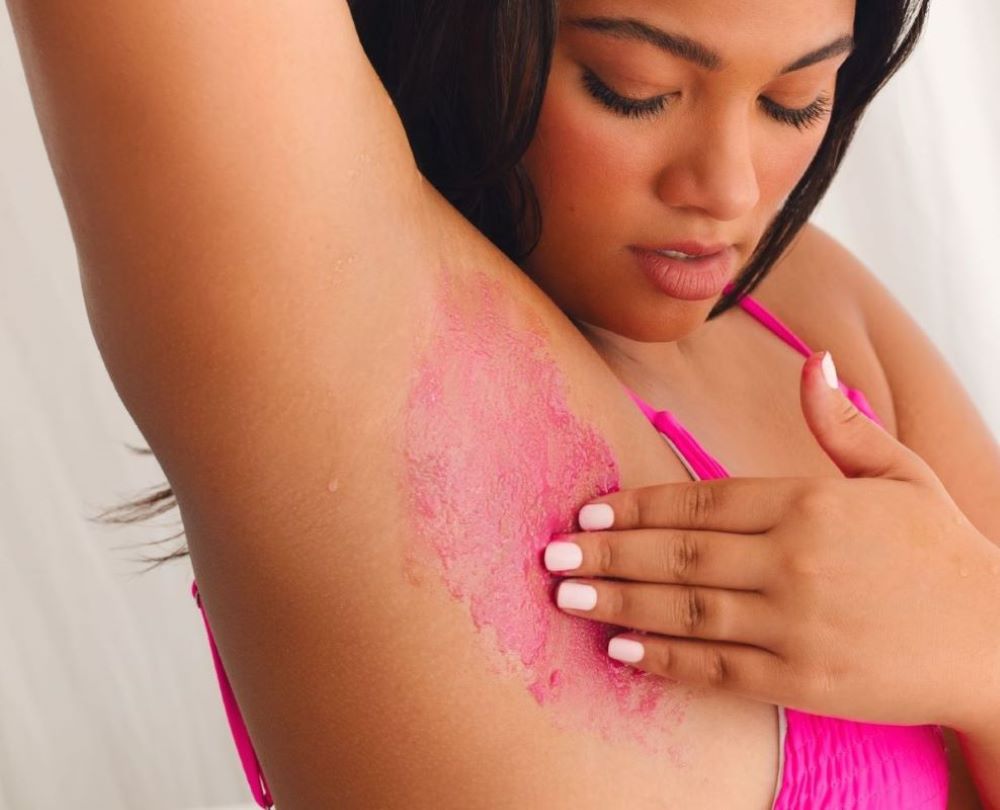 Do you exfoliate before or after shaving | woman applying pink body scrub to armpits