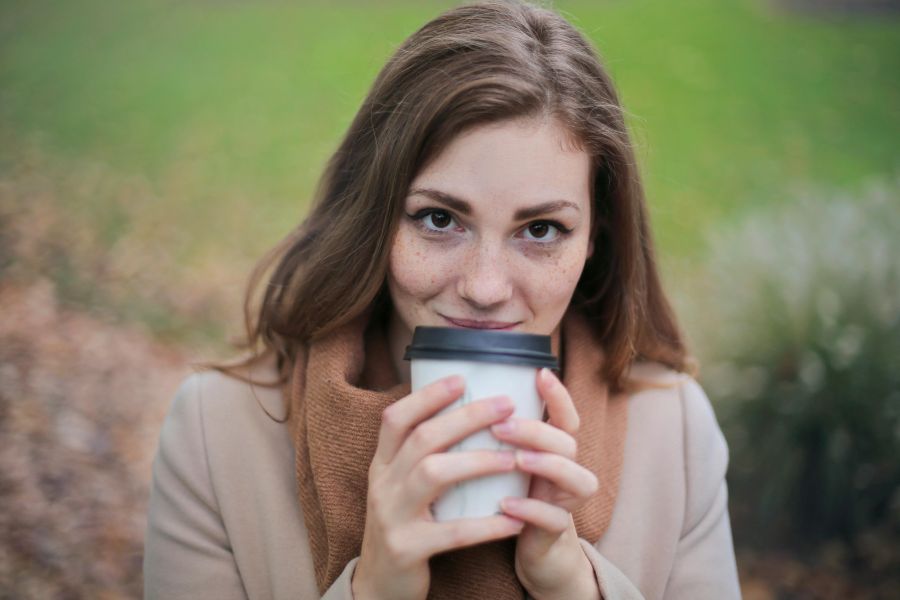 fall skincare tips | Woman in Brown Top and Scarf Holding a White Travel Cup Outside