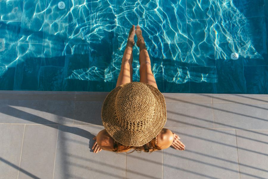 how long does a spray tan last | woman wearing sunhat with feet in pool