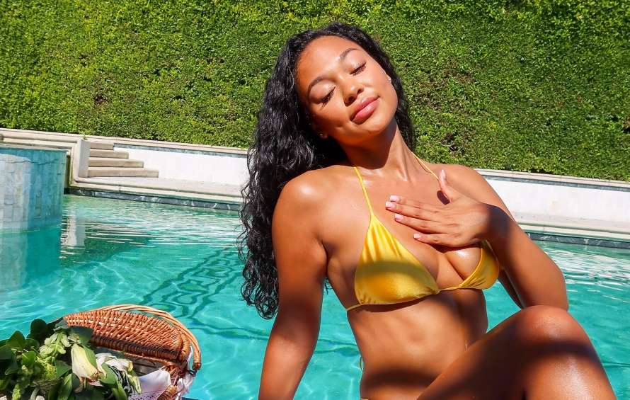 young woman in bikini sunbathing in front of pool