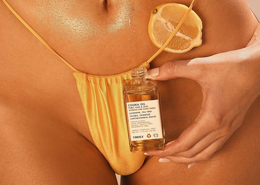 how to get rid of razor bumps fast | closeup of woman in orange bikini holding truly's cooka oil