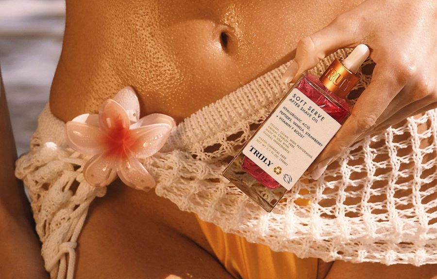 how to prevent ingrown hairs after shaving | Young woman holding Truly's soft serve shave serum in front of bikini area