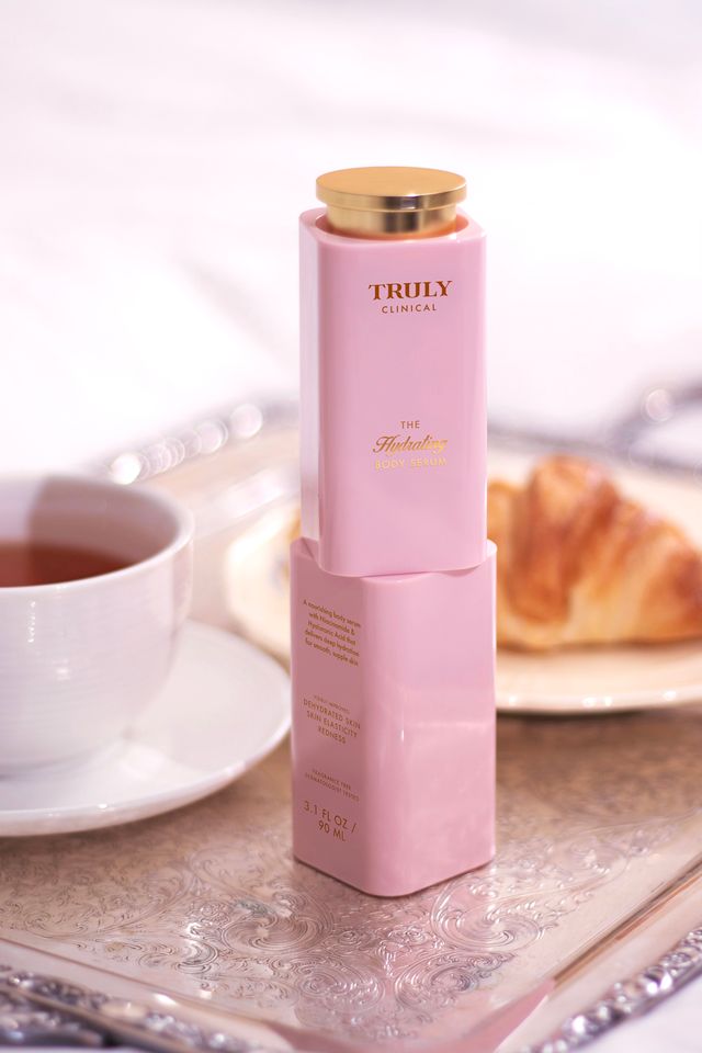 closeup of Trulys the hydrating serum on silver plate with cup of tea and croissant in background