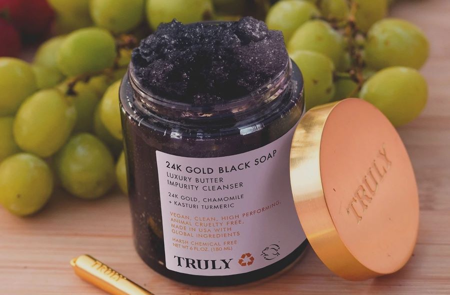 is salicylic acid good for sensitive skin | Truly's 24k gold black soap cleanser with lid off on table with green grapes