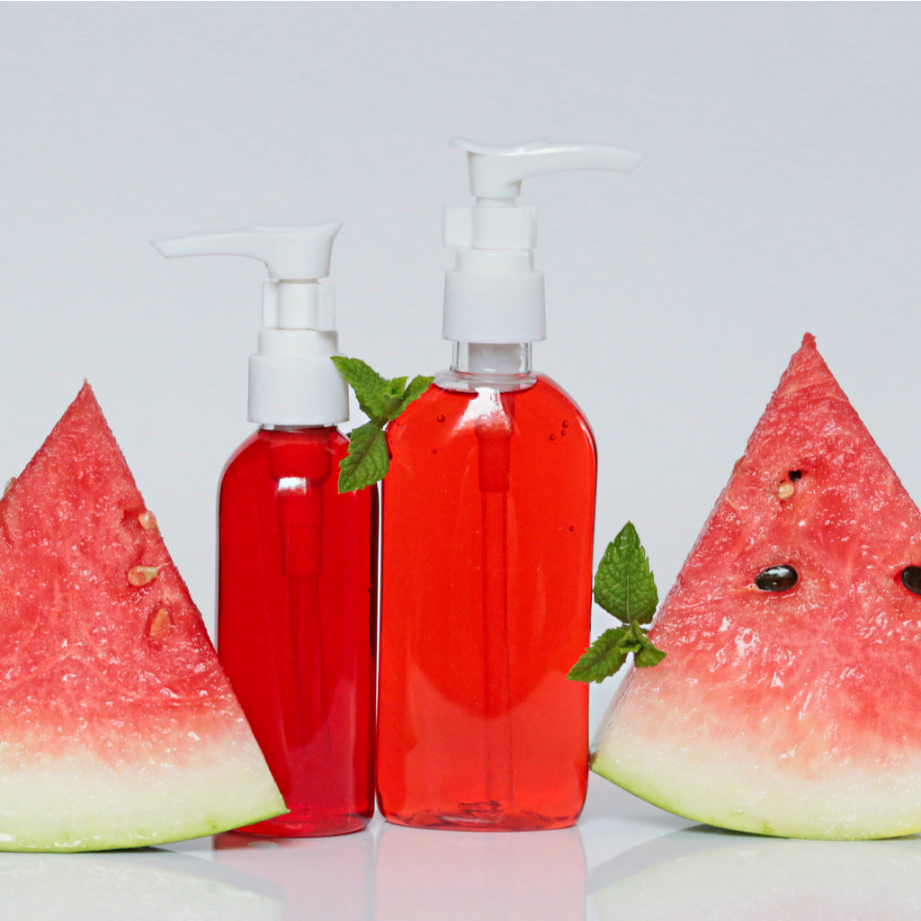 two bottles of red liquid surrounded by watermelon slices