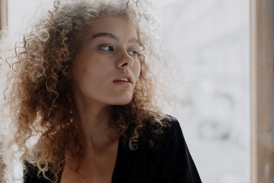 sagging skin | Curly haired woman looking over shoulder