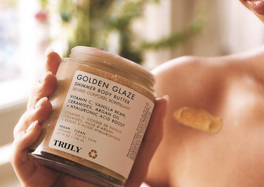 should you moisturize before self tanning | woman holding open jar of truly's golden glaze body butter