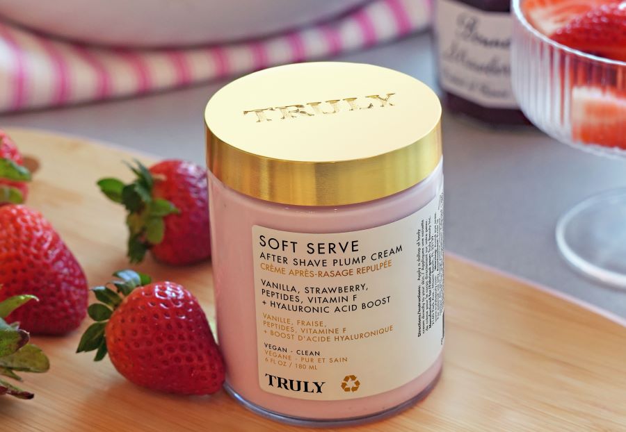 strawberry benefits for skin | Truly's soft serve after shave plump cream on wooden table beside fresh strawberries