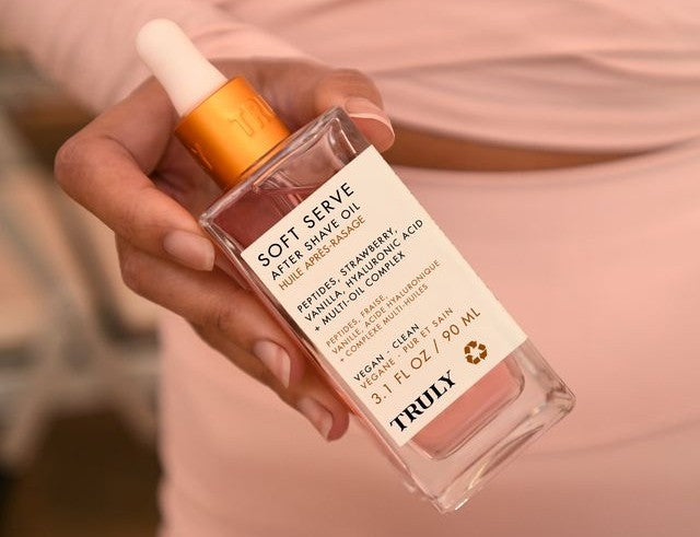 what is hyaluronic acid | closeup of woman wearing pink holidng bottle of Truly's soft serve oil 