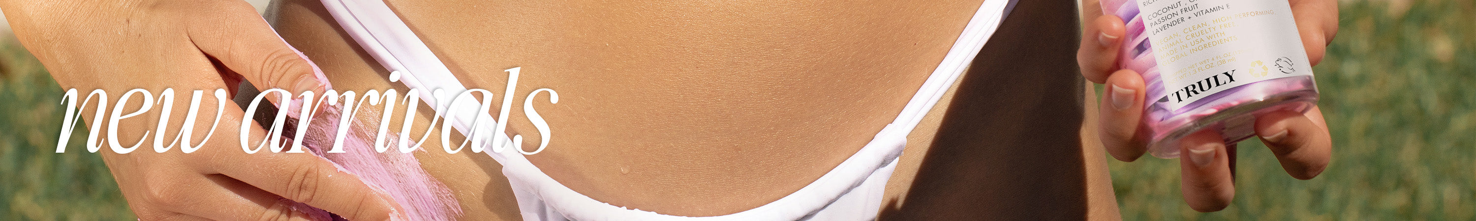 Close-up of a person in a white bikini holding a jar of Truly beauty product, with the text new arrivals overlaid on the image.