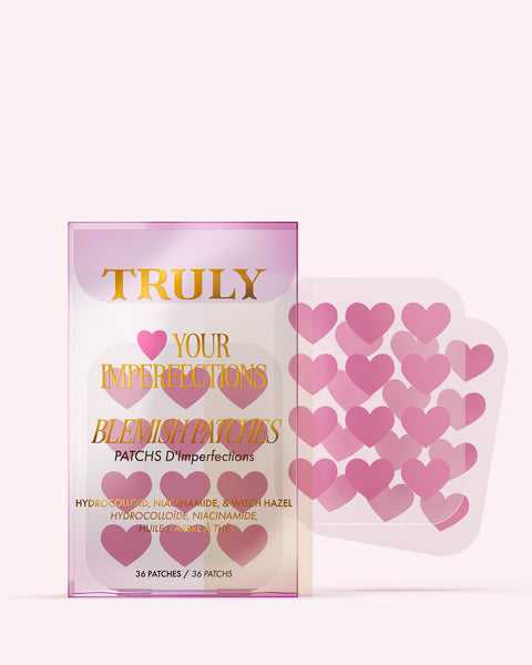 A package of Truly Beauty’s #Heart Your Imperfections Blemish Patches, featuring pink, heart-shaped hydrocolloid patches and bold pink and gold packaging that reads “TRULY Love Your Imperfections.”.