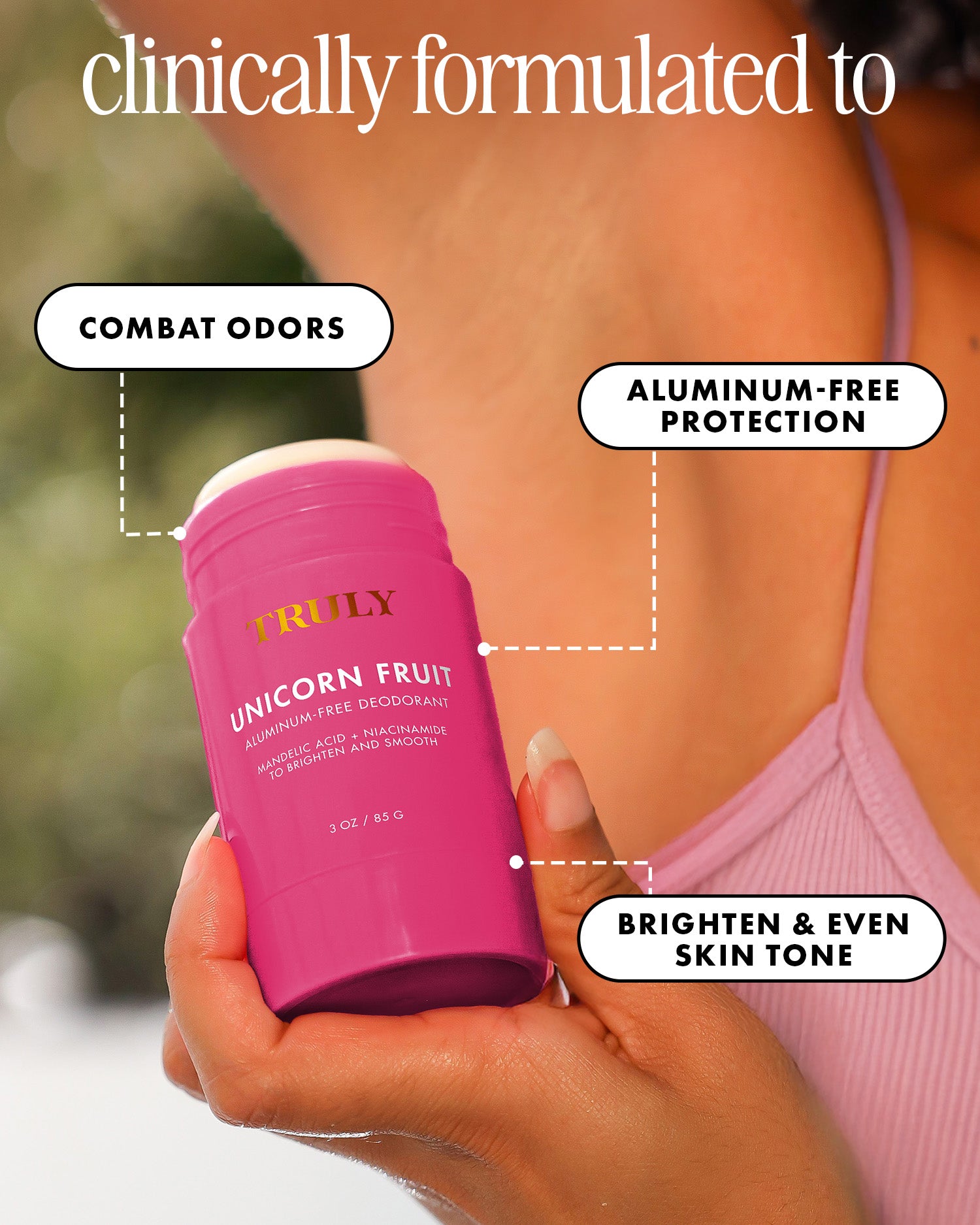 A hand holds a pink Truly Beauty Unicorn Fruit Skin Brightening and Smoothing Deodorant. Text highlights its benefits: combats odors, brightens underarms with niacinamide, and evens skin tone. Part of a person's shoulder and arm appears in the background.