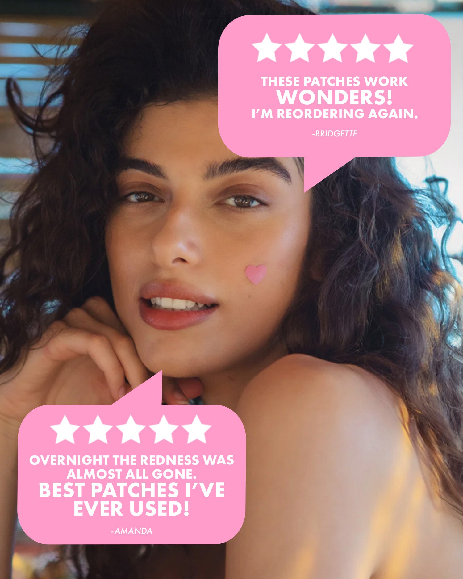 A woman with long, wavy hair rests her chin on her hand, wearing Truly Beauty’s #Heart Your Imperfections Blemish Patch. Reviews call these pink heart-shaped patches wonders and the best blemish treatment they've ever tried.