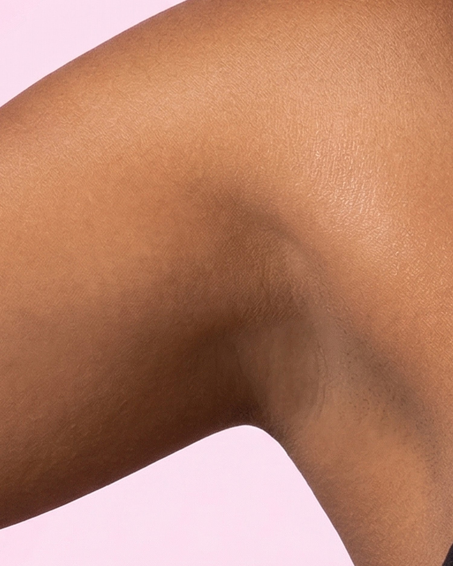 Close-up of a bent arm with a smooth, even-toned armpit—free from discoloration—thanks to Truly Beauty’s Coco Cloud Ingrown Prevention and Brightening Deodorant, set against a soft pink background.