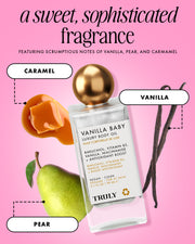 A bottle of Truly Beauty's Vanilla Baby Luxury Body Oil is displayed among caramel, vanilla beans, and a pear on a pink background, emphasizing its sweet fragrance notes of vanilla, pear, and caramel.