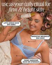 A smiling woman in a blue bra and pink rollers applies Diamond Baby Treatment Body Serum by Truly Beauty to her forehead. Text highlights its benefits: lifting loose arm skin, smoothing chest wrinkles, and firming sagging stomach skin.