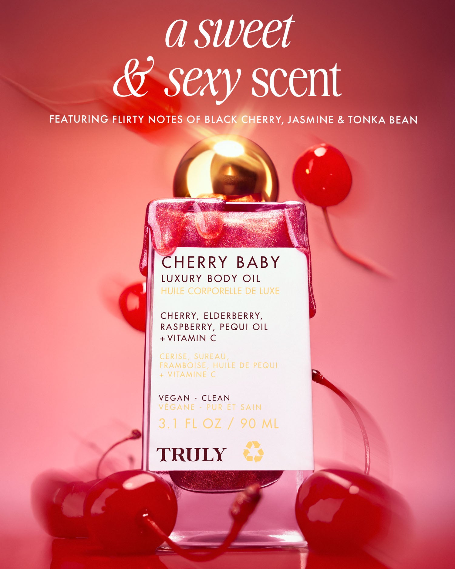A bottle of Truly Beauty Cherry Baby Luxury Body Oil sits among cherries on a pink background. “A sweet & sexy scent” appears above, highlighting its fragrance notes and key hydrating ingredients for glowing skin.