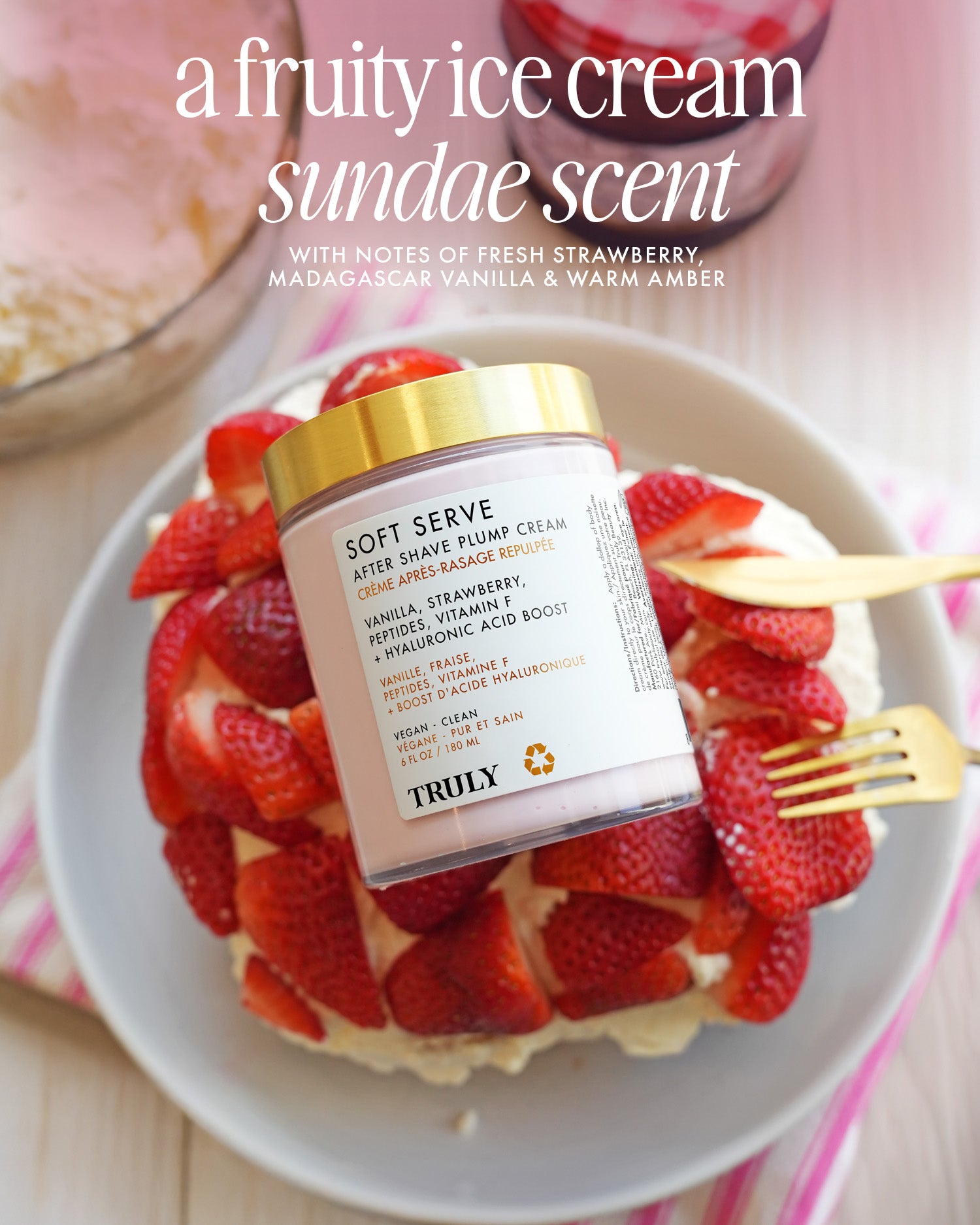 A jar of Truly Beauty’s Soft Serve After Shave Plump Cream sits on a plate with strawberries and whipped cream, next to a glass jar, spoon, and dish of pink ice cream. Text showcases its hydrating benefits and sundae-inspired scent.