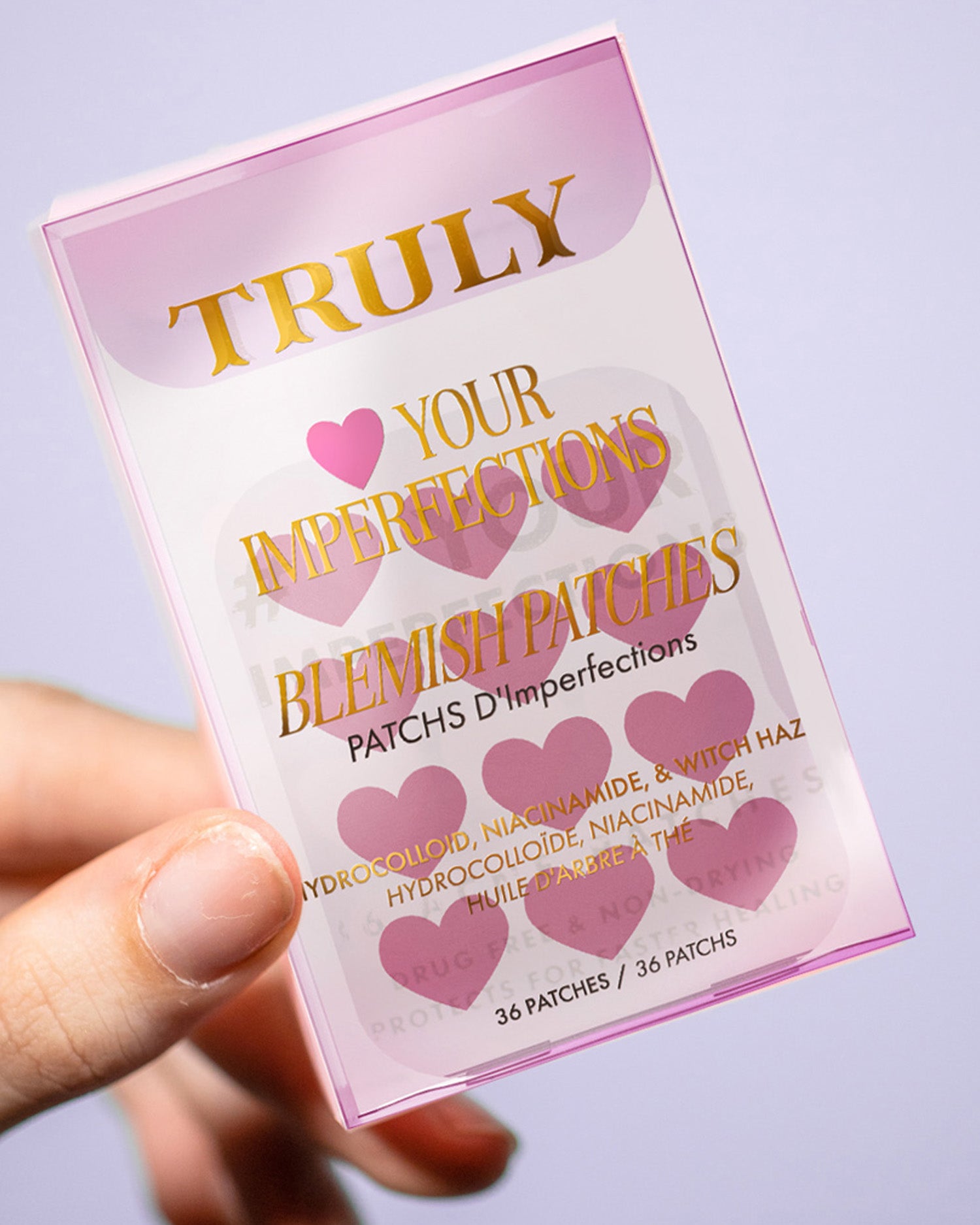 A hand holds a translucent pink packet labeled Truly Beauty #Heart Your Imperfections Blemish Patches, featuring hydrocolloid, niacinamide, and witch hazel. The pack includes 36 pimple patches for targeted blemish care.