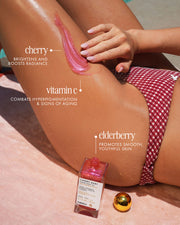 By the pool, a person in a red checkered bikini applies Truly Beauty Cherry Baby Luxury Body Oil to their leg—infused with cherry (brightens), vitamin C (fights aging), and elderberry (smooths skin) for a radiant shimmer.