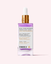 A bottle of Truly Beauty Acai Your Boobies Firming Body Serum with a gold dropper cap, highlighting its acai extract, retinol, apricot, and antioxidant-rich moisturizing formula on a light pink background.