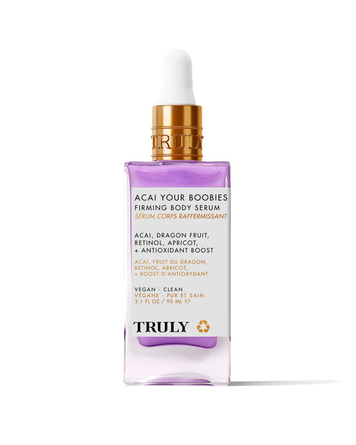 A bottle of Truly Beauty’s Acai Your Boobies Firming Body Serum with a purple liquid, gold dropper cap, and white label highlighting acai extract, retinol, and skin-moisturizing ingredients like dragon fruit.