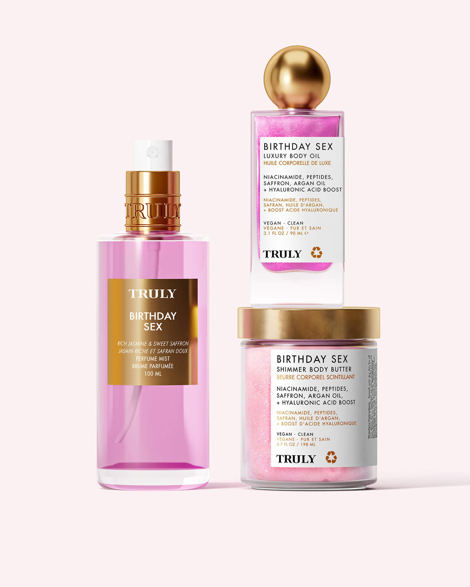 The Truly Beauty Birthday Sex Luxury Trio features a pink spray bottle of body oil with jasmine, a gold-lidded cube of body polish, and a jar of shimmer body butter, all displayed on a pale background.