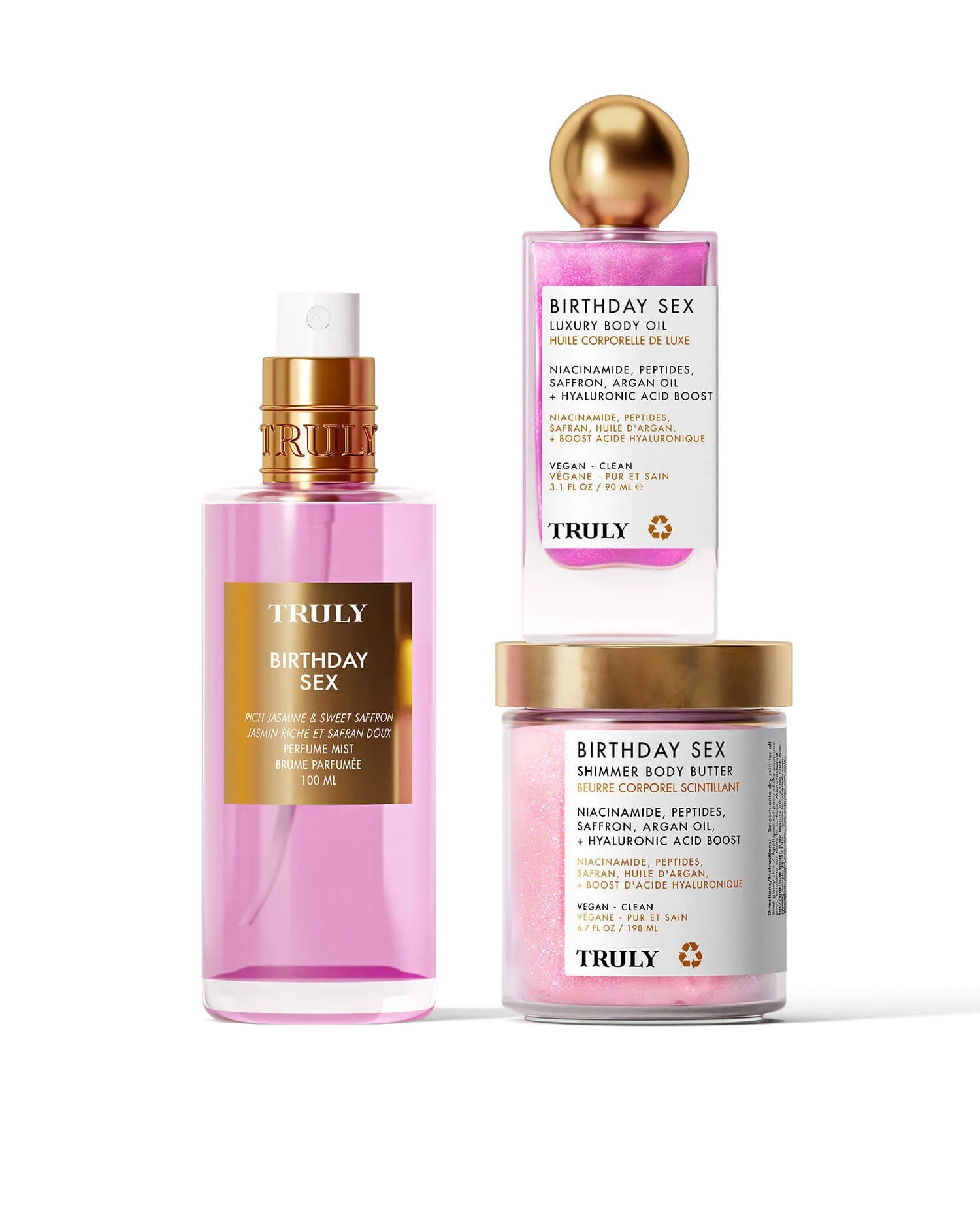 The Truly Beauty Birthday Sex Luxury Trio features a pink spray bottle of body oil with jasmine, a gold-lidded cube of body polish, and a jar of shimmer body butter, all displayed on a pale background.