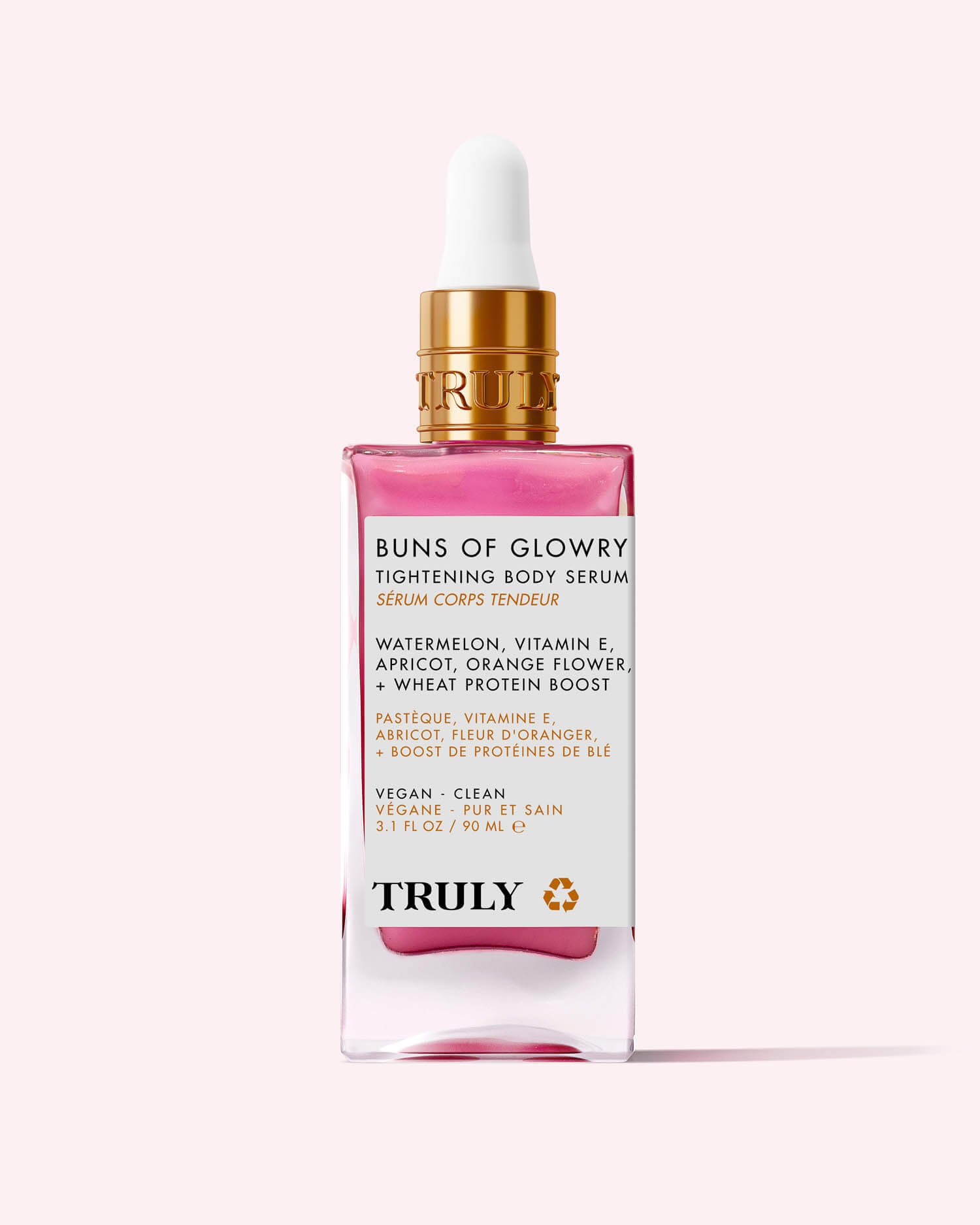 A pink and gold dropper bottle of Buns Of Glowry Tightening Body Serum by Truly, featuring ultra-hydrating serum with watermelon, vitamin E, apricot, orange flower, and wheat protein extract on a light pink background.