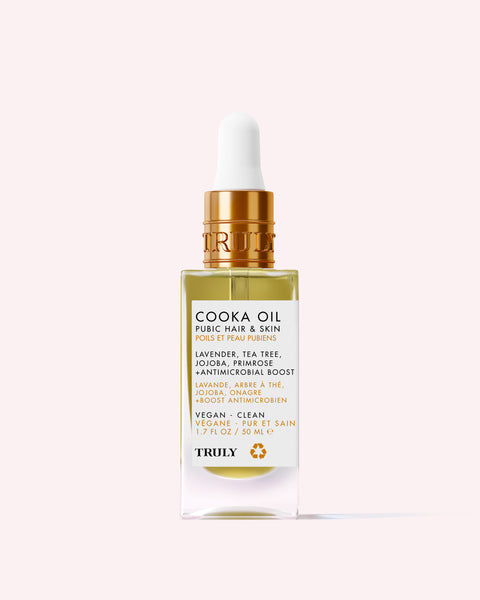 A clear dropper bottle of Cooka Oil by Truly Beauty for pubic hair and skin, featuring lavender, tea tree, jojoba, and primrose oils. The vegan, clean formula is antimicrobial and designed to help prevent ingrown hairs.