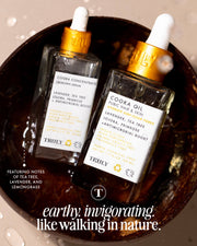 Two glass dropper bottles labeled Cooka Routine by Truly Beauty rest in a brown bowl; text highlights their natural ingredients and describes them as earthy, invigorating, and ideal for soothing pubic hair or targeting ingrowns.
