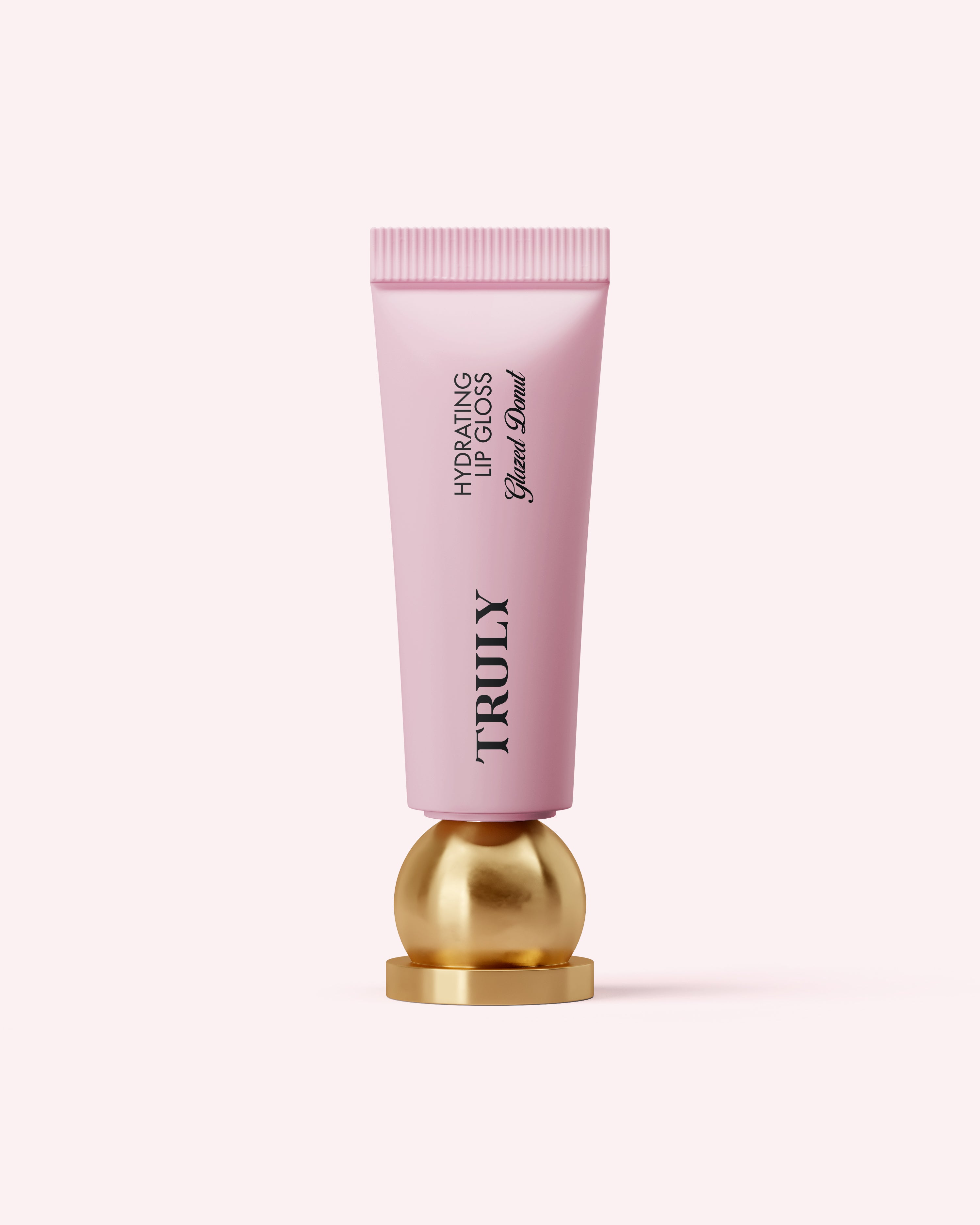 A pink tube of Truly Beauty Hydrating Lip Gloss with hyaluronic acid stands upright on a round, gold base against a light pink background.